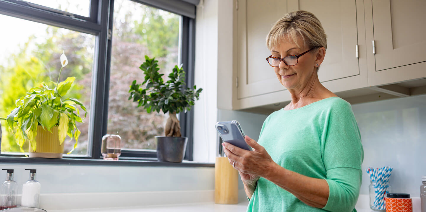 A woman in a kitchen looking down at her phone