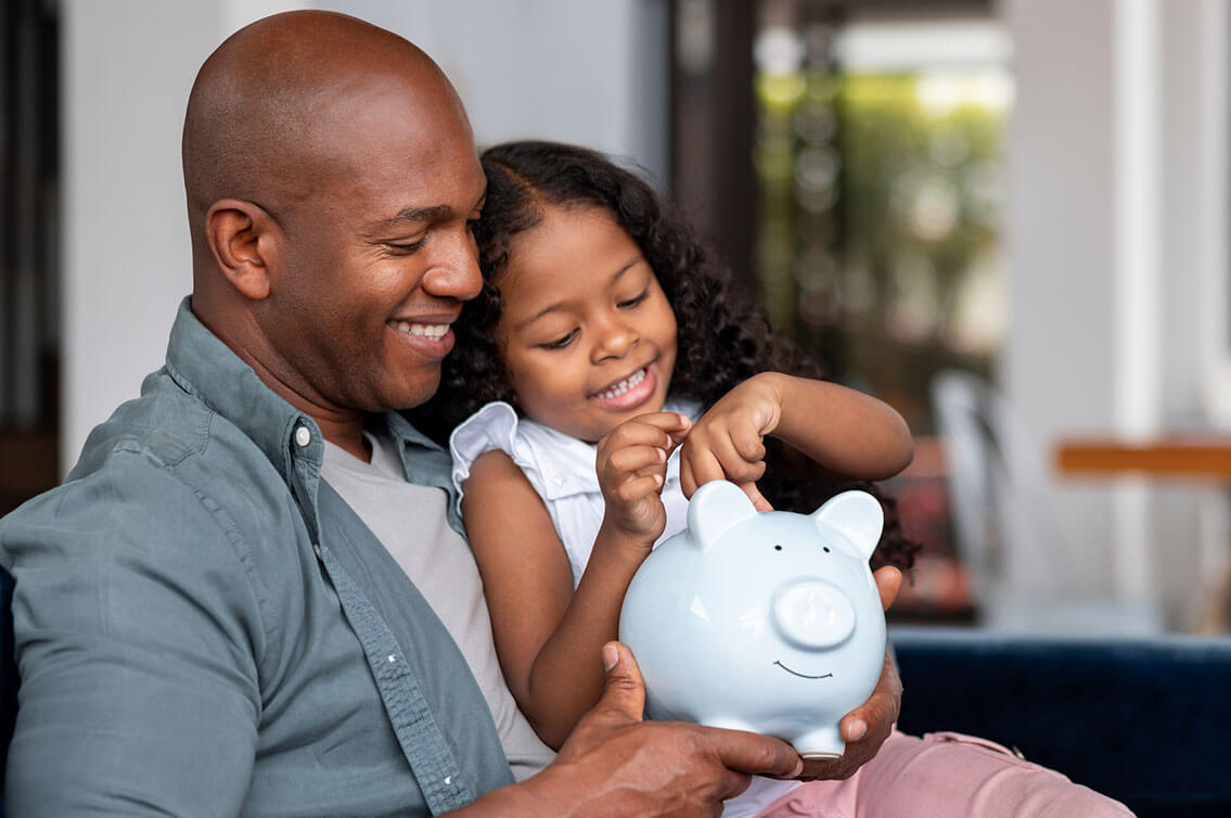 A young girl and man holding a piggy bank